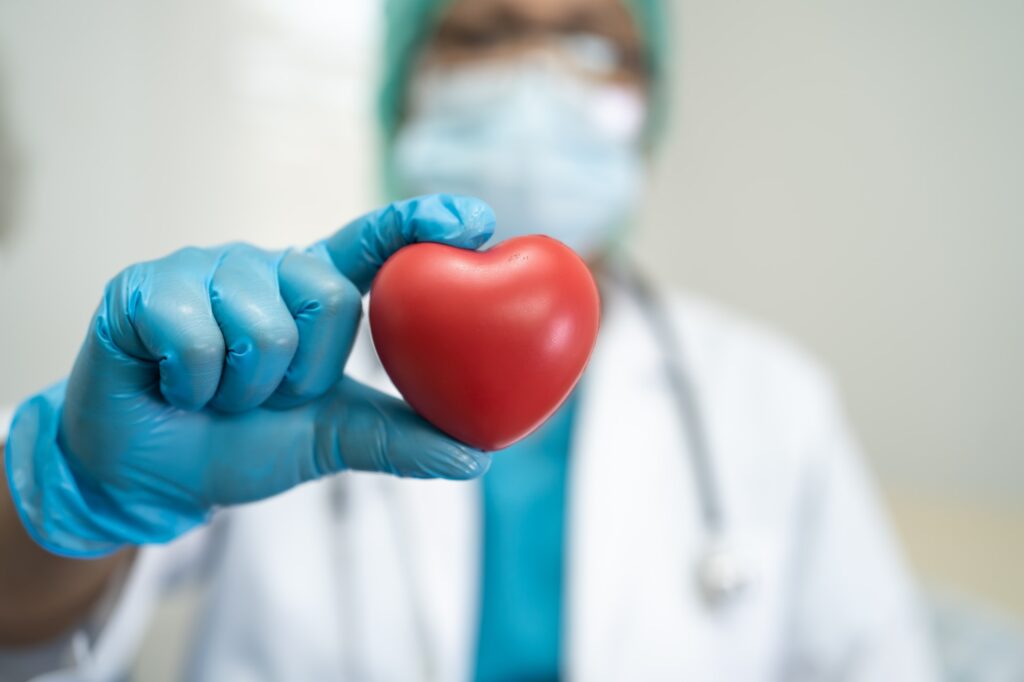 LONG-COVID Gripping Heart-Health. Doctor wearing ppe with mask for protect coronavirus holding red heart.